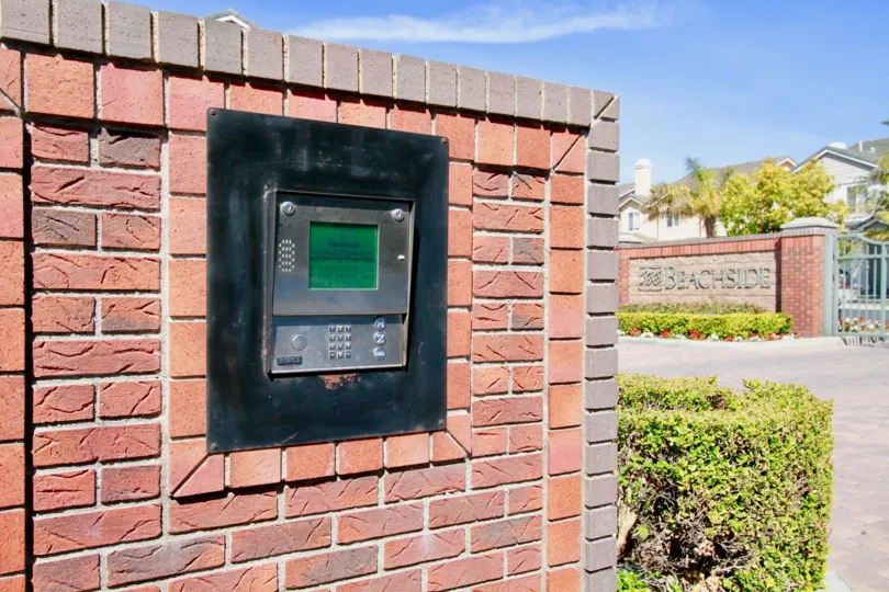 THE VIDEO CALLING AVAILABLE AT THE MAROON COLOUR WALL AND A BUILDING LOCATED AT THE RIGHT SIDE OF THE CALLING VIDEO AND SOME PLANTS ALSO AVAILABLE NEAR TO THE PLACES