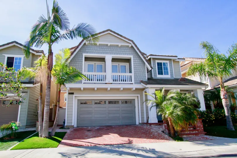 Beachside home with balconies and palm trees on a sunny day.