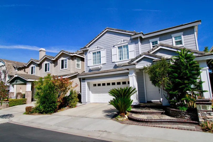Beachside Huntington Beach California house light blue color near tree and grasses
