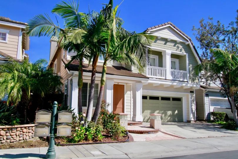 Beachside two story home with a garage and trees on a sunny day.