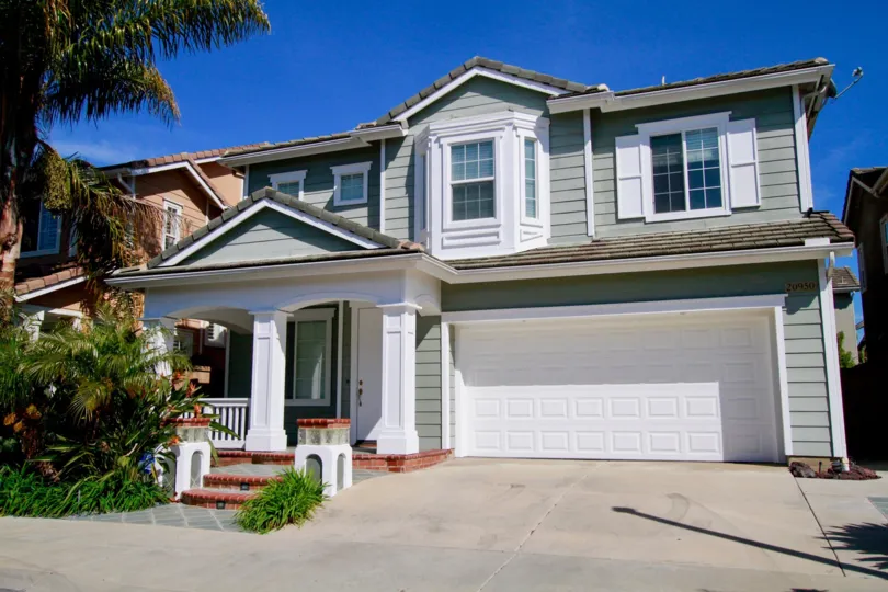 Beachside home with stairs and a palm tree on a sunny day.