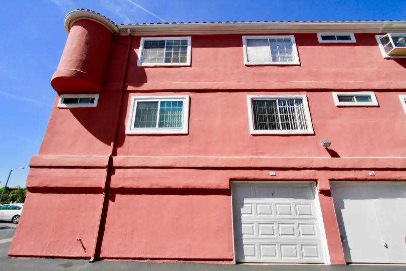 THE SINGLE BUILDING WITH THREE FLOORS AND MORE WINDOWS ALSO AVAILABLE AND A CAR PARKED AT THE SIDE OF THE BUILDING AND THE SKY LOOKING LIKE SUNSHINE.