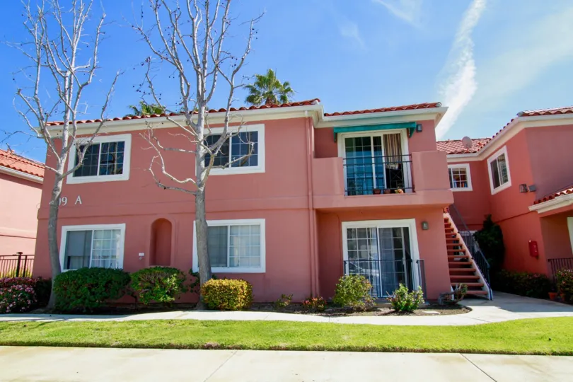 Brisas Del Mar pink apartments with trees and a staircase.