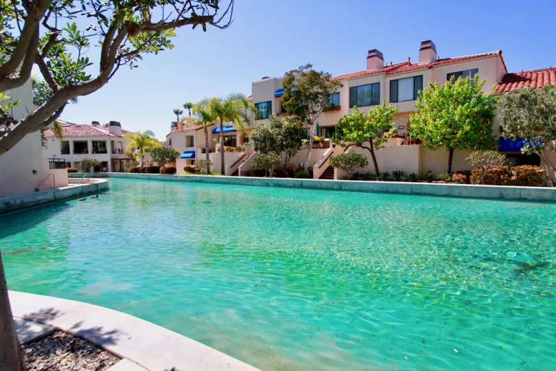 A sunny day with the pool and bright green landscaping at Broadmoor Huntington Harbor.