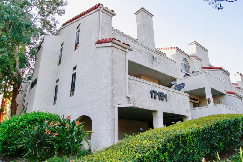 A big white apartment with number 17151 in the Cabo Del Mar with flowering plants and ornamental plants.
