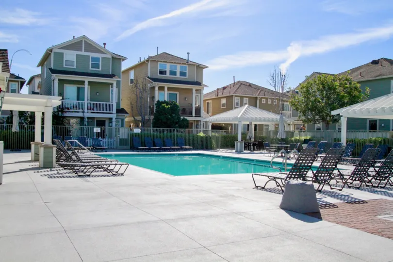 Cape Ann pool with deck chairs and gazebos on a sunny day.