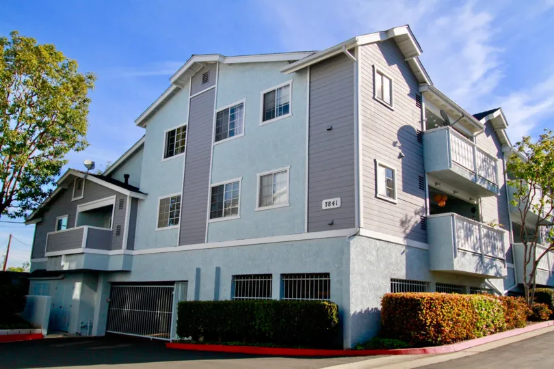 Capewoods apartment building with balconies and bushes on a sunny day.