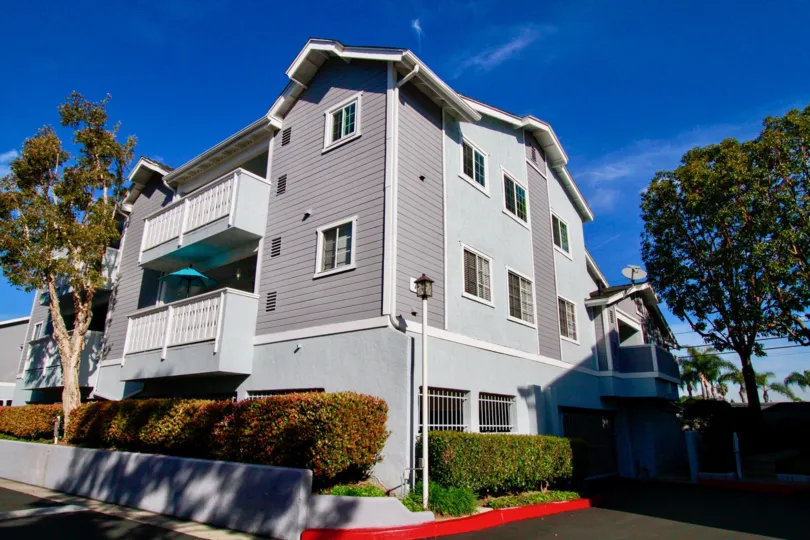 Capewoods apartment building with balconies and bushes on a sunny day.