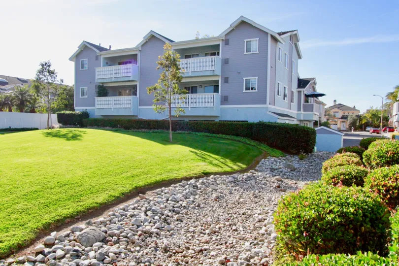 THE BUILDING LOOKS LIKE LONG SHOT AND MORE GRASS AT THE FRONT AND IT LOOKS LIKE A SMALL GARDEN AND PLANTS, TREES ALSO AVAILABLE AT THE MORNING TIME