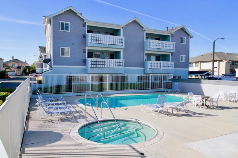 A SWIMMING POOL WITH A BIG HOUSE IN FRONT OD AND A SMALL POOL ALSO NEAR TO THE BIG ONE AND SOME RELAXATION CHAIRS ALSO AVAILABLE AT THE PLACE OF POOL