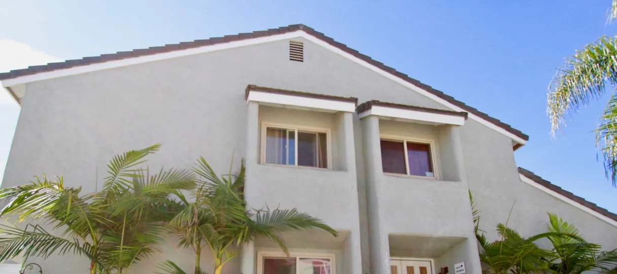 Cherrywood Village apartment with palm trees and windows on a sunny day.