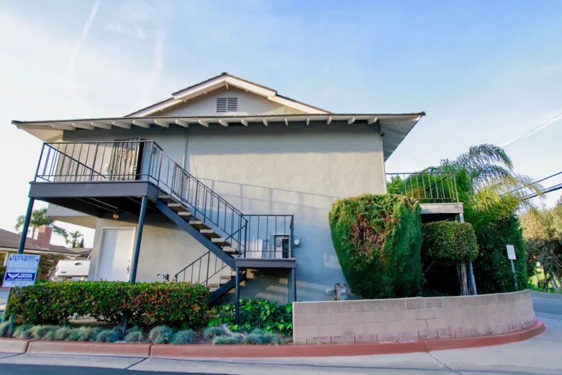 Fernhill apartments building with a staircase and fence on a sunny day.