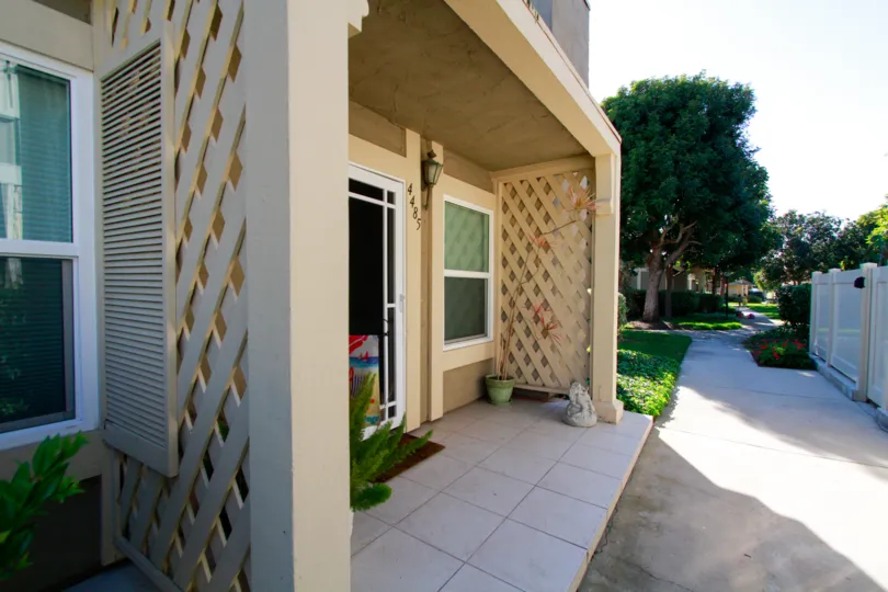 THE BUILDING WITH CUTE ENTRANCE AND THE DOOR CLOSED AND A SMALL PATH ALSO AVAILABLE AND SOME TREES ALSO NEAR TO THE HOUSE WITHIN THE ENTRANCE GATE