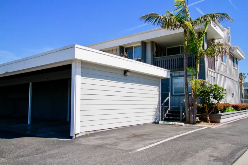 Harboring Villas building with garage and palm trees on a sunny day.