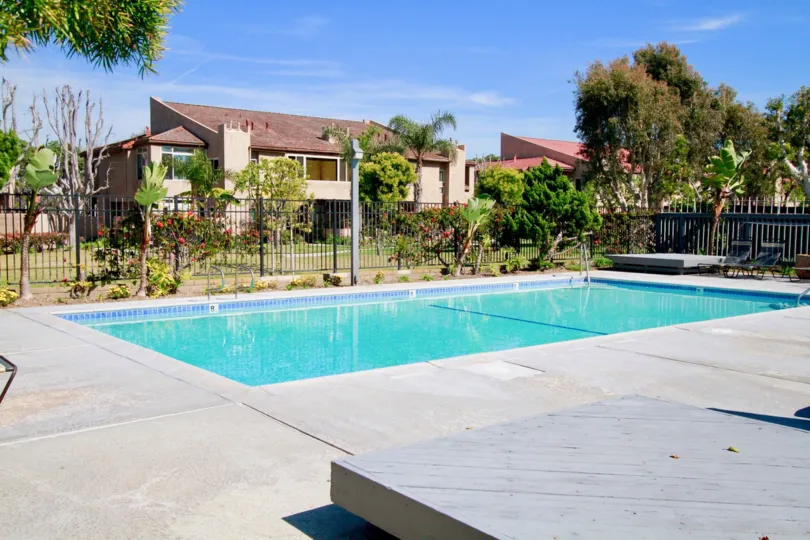 Harboring Villas pool with a fence and trees on a sunny day.