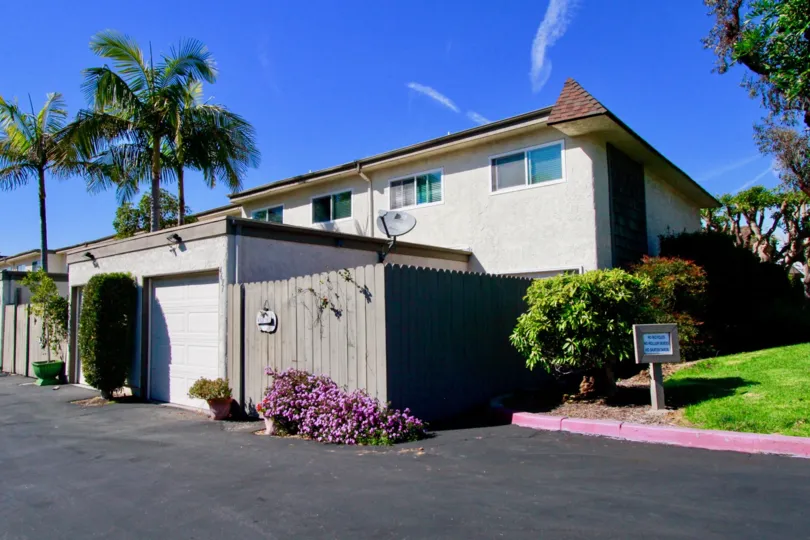 Harbour Village apartments with a fence and garages on a sunny day.