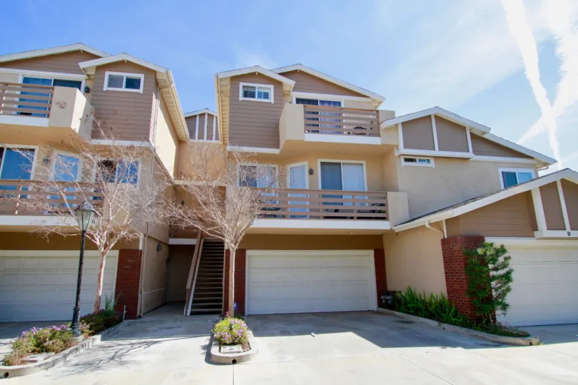 A big apartment with big doors in the Holly Street Townhomes with flowering plants near the road side.