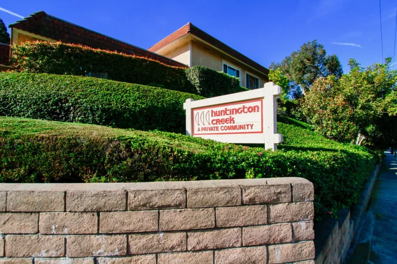 THE BUILDING ALONE AND A SIGN BOARD REPRESENTS HUNTINGTON CREEK AND IT LOOKS WHITE WITH PINK COLOUR AND A SMALL GARDEN NEAR TO THE HOUSE AND SOME TREES ALSO AVAILABLE.