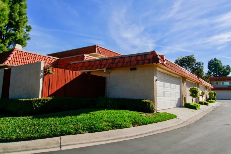 Huntington Creek building with a garage and red fence on a sunny day.