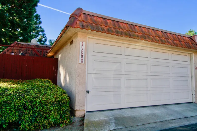 Huntington Creek garage with a fence and bushes on a sunny day.
