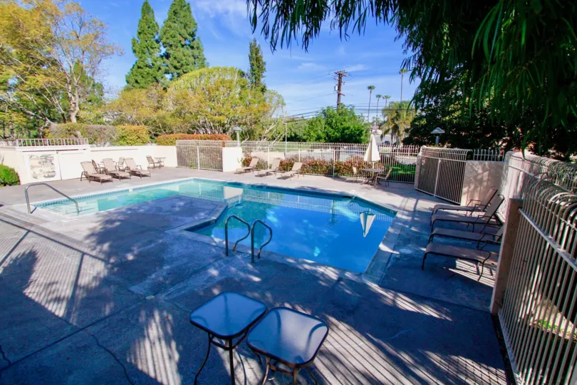 Huntington Creek community pool with deck chairs and tables on a sunny day.