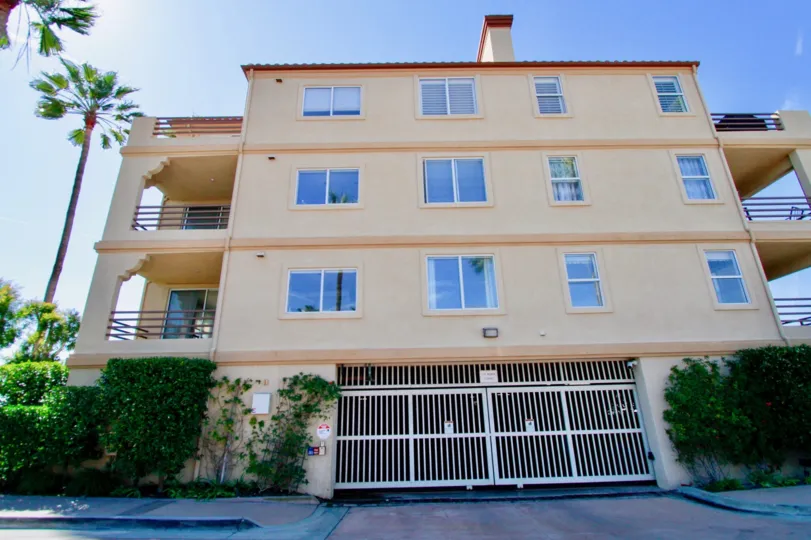 Huntington Harbour Bay Club apartments with a gate and balconies on a sunny day.