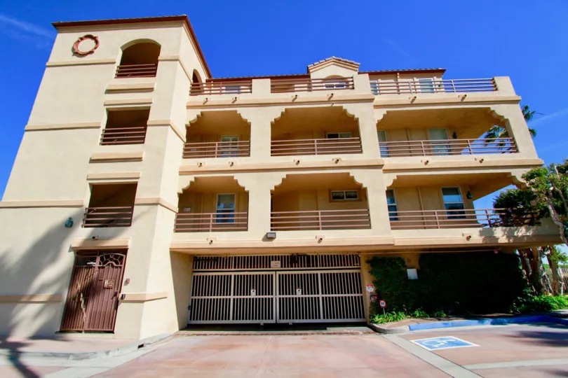Huntington Harbour Bay Club apartments with a gate and balconies on a sunny day.