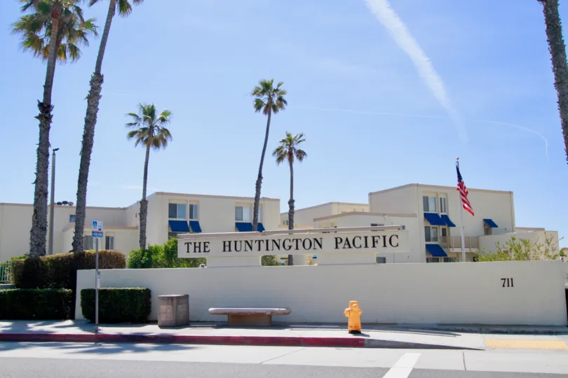 Huntington Pacific sign with a fence and palm trees on a sunny day.
