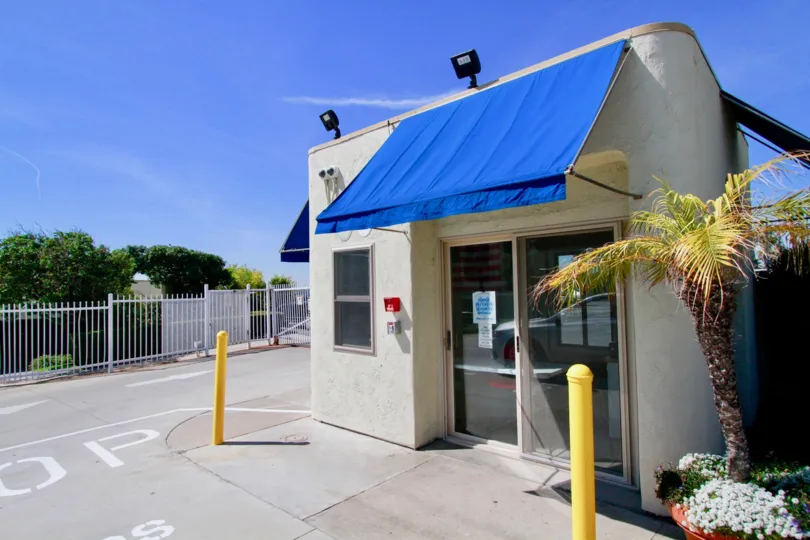 Huntington Pacific building with a palm three and blue awning on a sunny day.