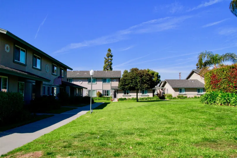 Huntington Townhomes sidewalk with buildings and trees on a sunny day.