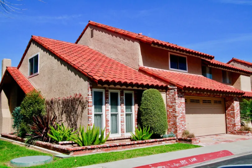 La Cuesta Racquet Club homes with red bricks and a garage on a sunny day.