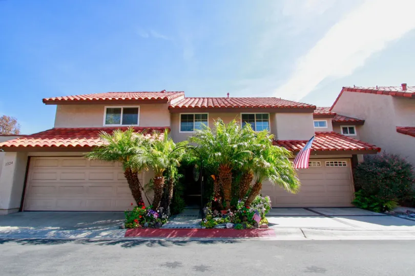 La Cuesta Racquet Club duplex with garages and palm trees on a sunny day.