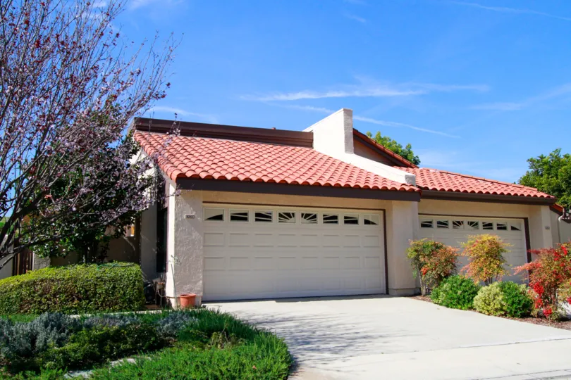 A house with big doors in the Landmark Yorktown with flowering plants, ornamental plants, trees and shrubs.