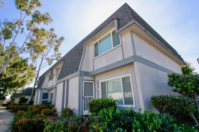Mariners Cove West two story building with bushes and trees around it.