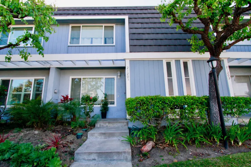 Mariners Cove two story building with trees and a sidewalk.