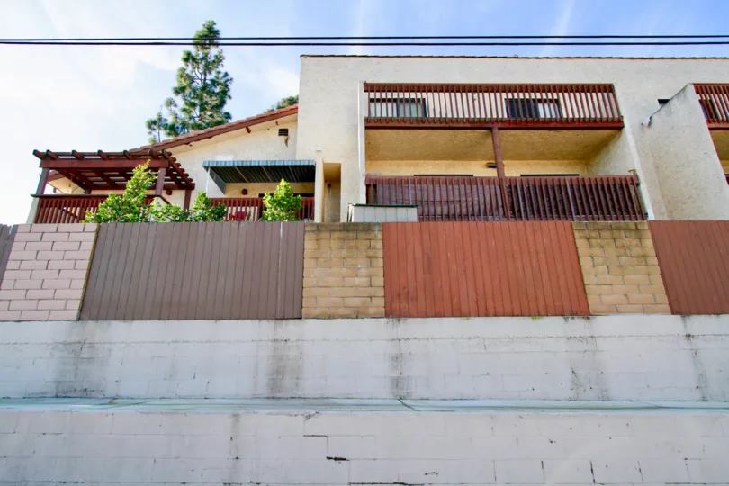 Newman Terrace apartment building with a fence and trees on a sunny day.