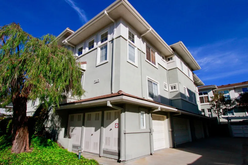 Pacific Park Villas building with garages and trees on a sunny day.