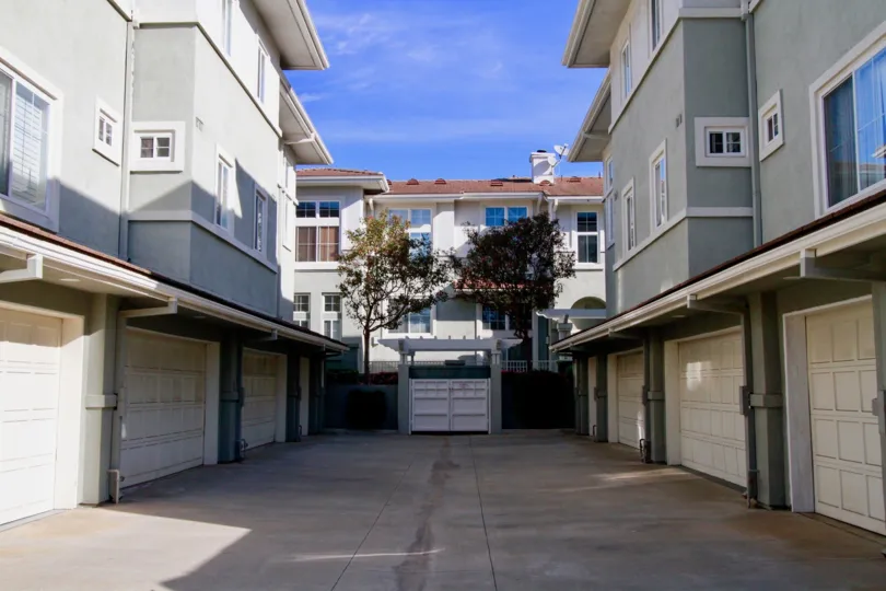 THE APARTMENTS LOOKING LIKE PARALLEL VIEW AND A PATH ALSO AVAILABLE AT THE CENTRE OF THE BUILDINGS AND SOME TREES ALSO AVAILABLE AT THE MORNING TIME.