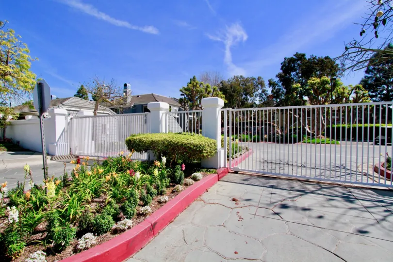 Pacific Ranch Townhomes gate with flowers and bushes in front of it.