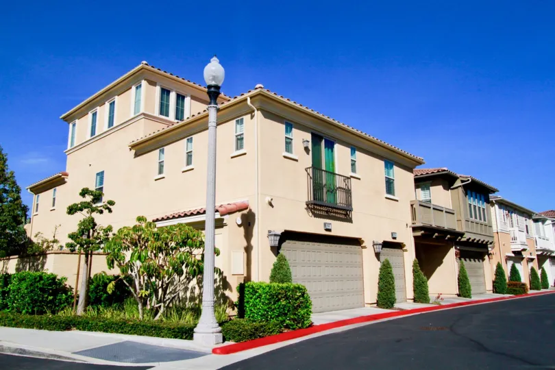 Pacific Shores Huntington Beach California building light rose color paint front glass window balcony attached big tree front side lamp post attached