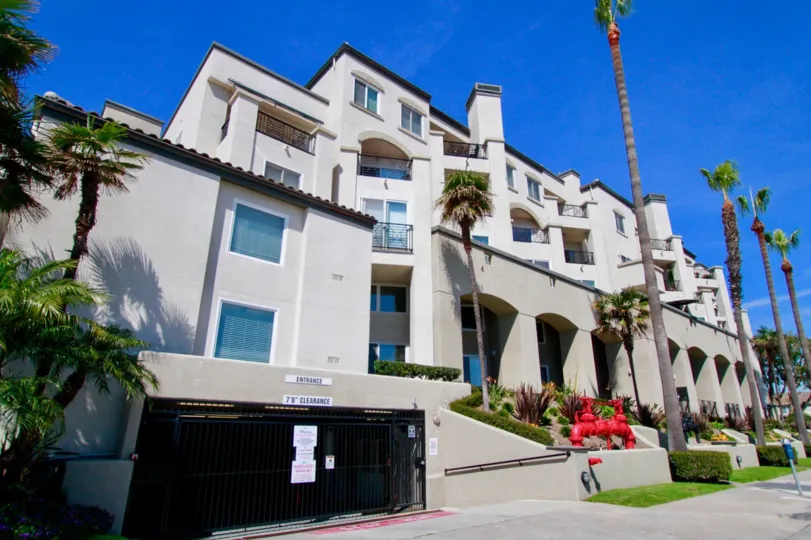 Pier Colony apartment building with palm trees and a gate.