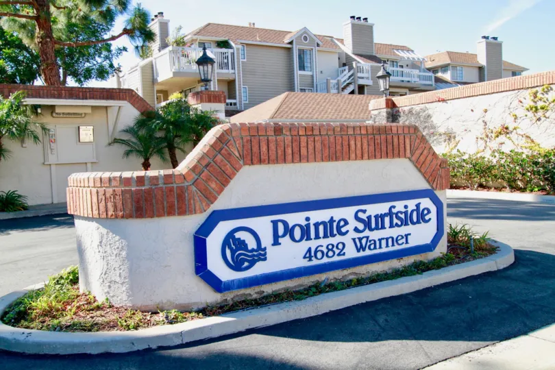 Pointe Surfside sign with a fence and roundabout on a sunny day.