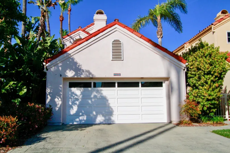 Portofino Cove home with palm trees and a garage on a sunny day.