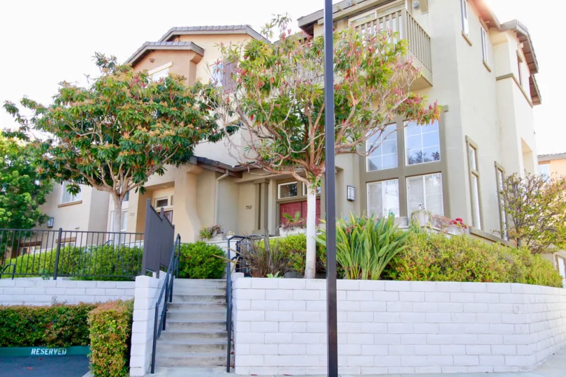 Promenade homes with a stair case and trees in front of it.