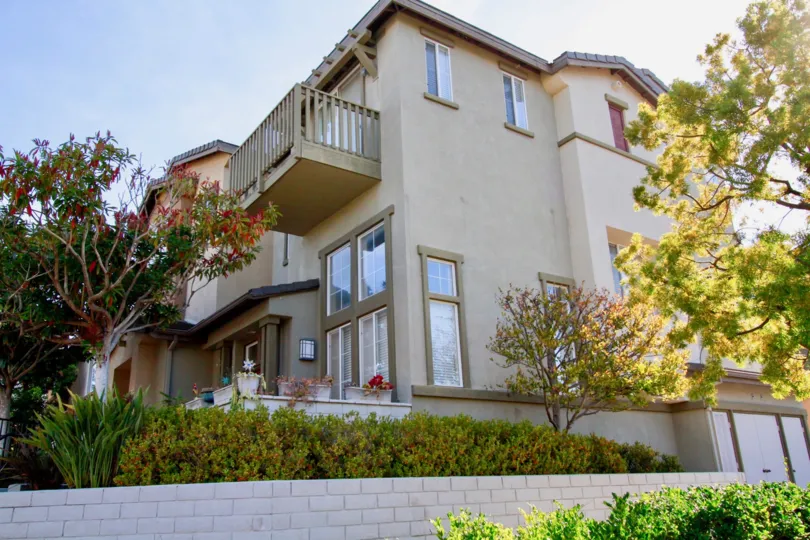 Three story house on a sunny day with a beautiful yard and nice landscaping