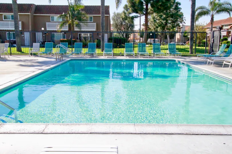 A sunny day by the pool in Huntington Beach with lawn chairs and privacy fence.