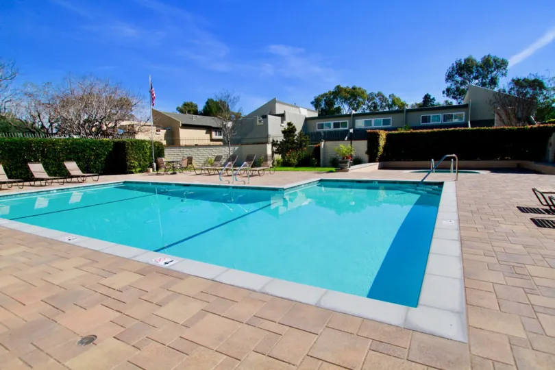 Sea Breeze Village pool with deck chairs and a fence on a sunny day.