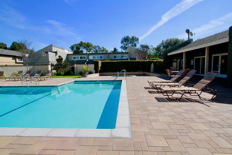 Sea Breeze Village pool with deck chairs and a fence on a sunny day.