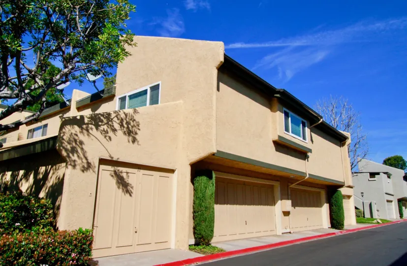 Sea Breeze Village apartment building with two garages and bushes on a sunny day.