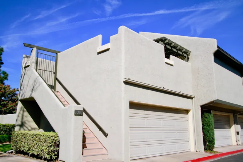 Sea Breeze Village apartments with a staircase and garage on a sunny day.